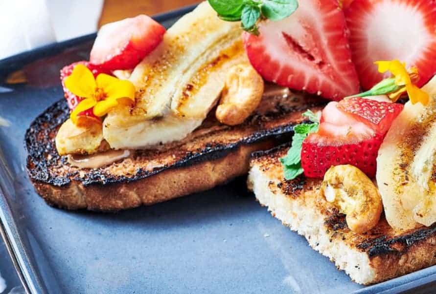 Toast with sliced banana, strawberries and maple syrup