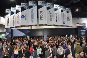 A room full of people underneath company banners from a previous Informa Tech International Wireless Communications Expo.