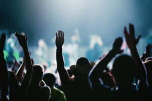 Rear view of a large group of people enjoying a concert performance at a musical festival. 