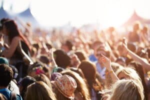 Audience at an outdoor music festival with their hands in the air.