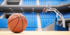 focus is on a basketball on a basketball court, the net is hanging in the background.