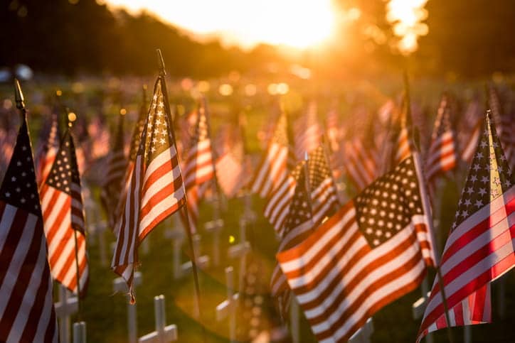 Countless American flags in the grass near grave markers for Memorial Day.