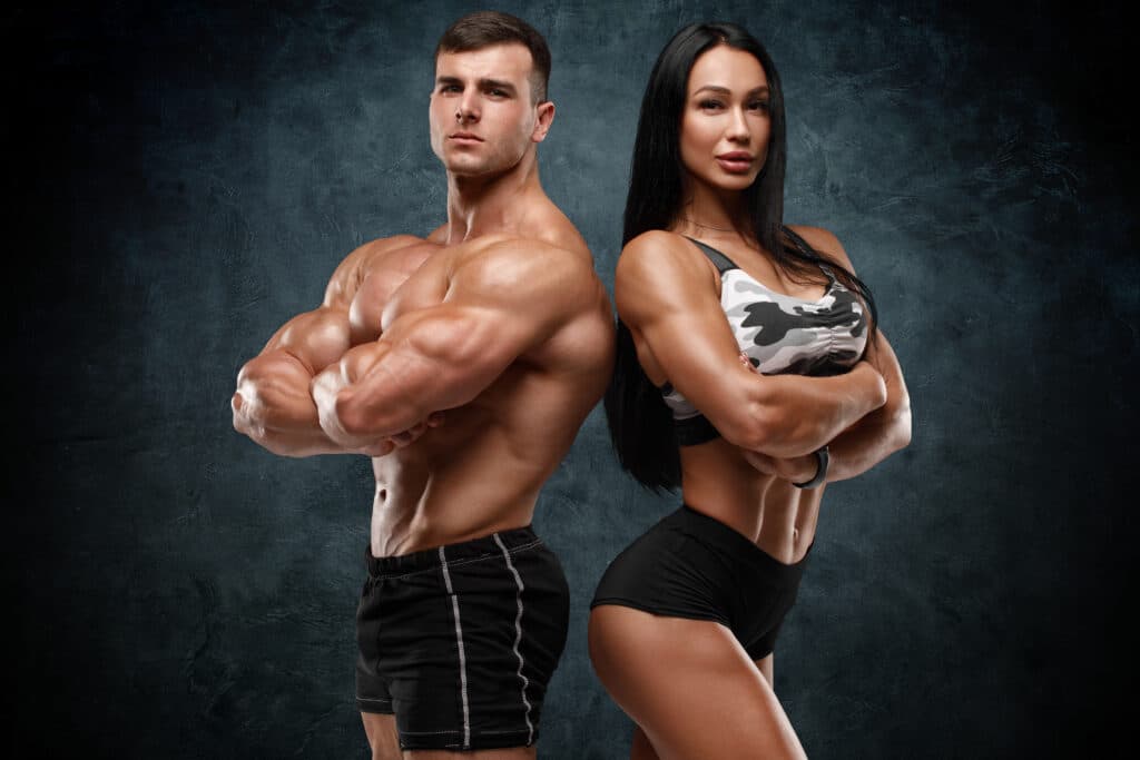Sporty Couple Showing Muscles. Muscular Man And Woman
