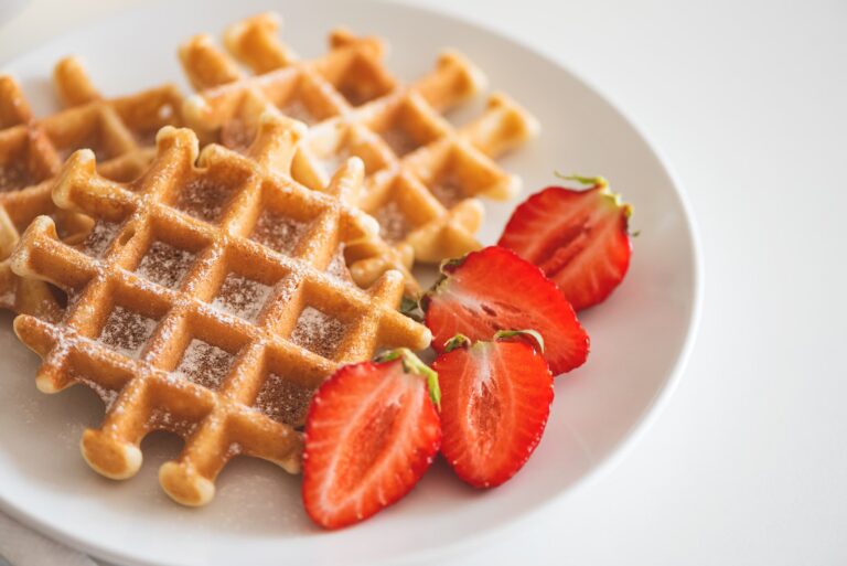 waffles on white plate with cut strawberries